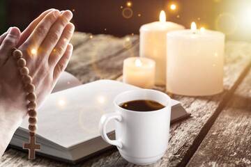Human hand  prays while reading the open bible, with a coffee cup on wooden table