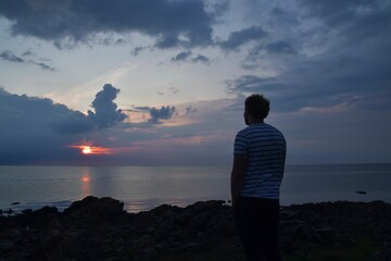 Landscape photo of person watching sea at sunset