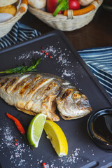 Grilled fish on a plate with a glass of wine and baked vegetables. 