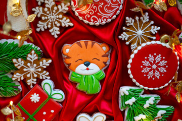 Banner for Christmas and New Year gingerbread tiger symbol Chinese zodiac calendar 2022 and gingerbread cookies snowflakes, Christmas trees, garlands on red silk fabric background