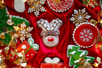 Fototapeta na wymiar Banner for Christmas and New Year gingerbread cookies deer, Santa Claus, snowflakes, Christmas trees, garlands on red silk fabric background