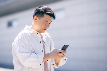 Asian young man walking down the street and using browsing social networks