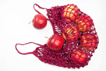 fruits apples red in a knitted string bag on an isolated white background