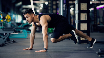 Fototapeta na wymiar Confident Muscular Arab Guy Making Running Plank Exercise While Training In Gym