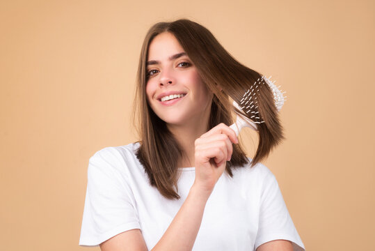 Brushing Hair. Portrait young woman brushing straight natural hair with comb. Girl combing long hair with hairbrush. Hair care beauty concept.