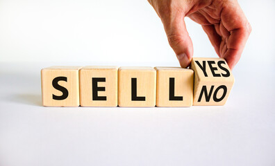 Time to sell symbol. Businessman turns a wooden cube and changes the words sell no to sell yes. Beautiful white table, white background. Business and time to sell concept. Copy space.