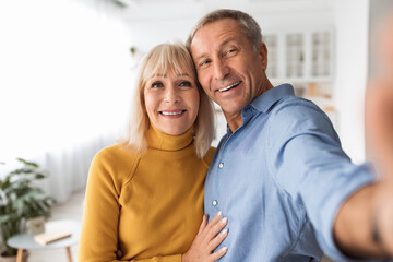 Obraz na płótnie Canvas Happy Senior Couple Making Selfie Hugging Standing At Home