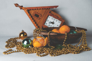 the photo shows a New Year's still life with a vase, fruits, tangerines, Christmas toys of gold and...