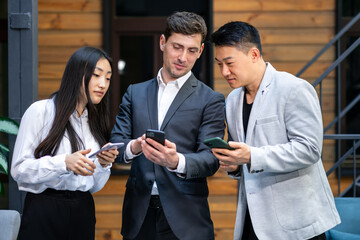 Business meeting and teamwork concept. Asian colleagues are discussing the project report using a mobile phone.