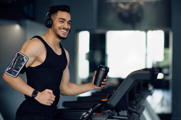Happy Young Middle Eastern Male Athlete Jogging On Treadmill At Gym