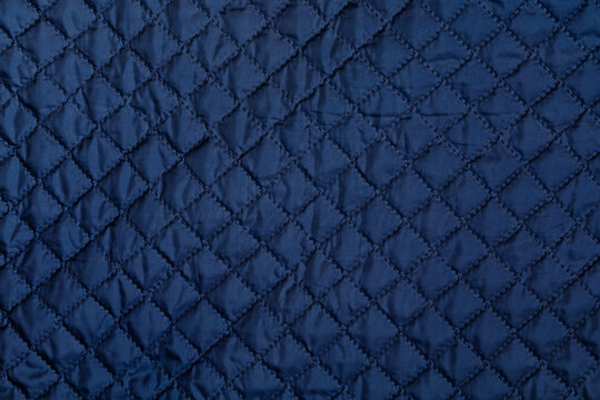 Blue texture of puffer, padded, down jacket. Background of urban winter outfit. Quilted pattern