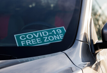 Covid-19 free zone. A cardboard sign on the windshield inside the car.