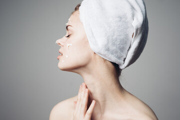 woman with bare shoulders towel on head face cream skin care