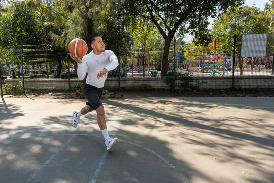 Entrenador latino corriendo hacia canasta de baloncesto en cancha de la Ciudad de M&eacute;xico
