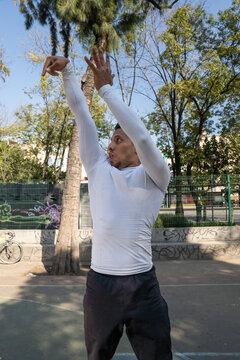 Entrenador latino lanzando tiro de baloncesto en cancha de la Ciudad de M&eacute;xico