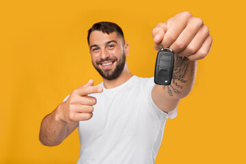 Smiling successful satisfied handsome adult caucasian man in white t-shirt show finger at key of new car
