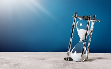 An hourglass with little time left sand on the desk.
