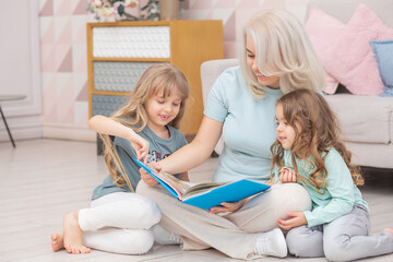 Obraz premium Caucasian mom reading a book to children sitting on the floor
