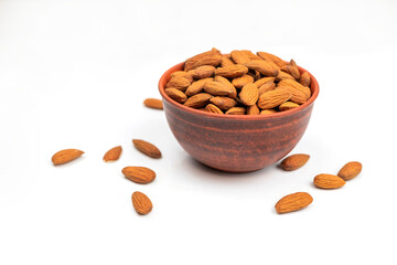 brown healthy tasty nut almonds in a clay plate on an isolated white background