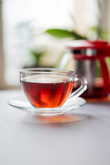 fragrant hot black English tea in a glass transparent cup with a teapot