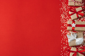 Above view of gift boxes and shiny confetti stars on red paper background