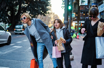 Happy women with purchases waiting for a taxi in the city