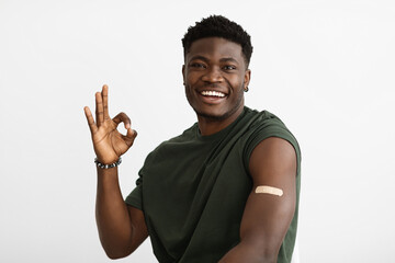 Smiling african american male patient got vaccinated, showing okay