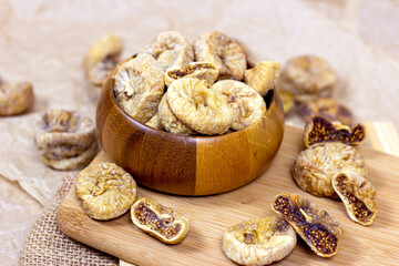 Sweet dried italian figs in the wooden bowl on the brown cutting board background.