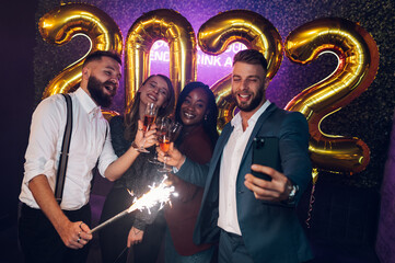Happy group of friends celebrate New Year's Eve and taking selfie with a smartphone