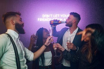 Friends dancing on a party in a club while drinking champagne