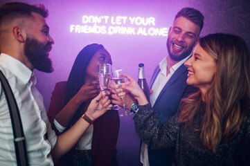 Friends dancing on a party in a club while drinking champagne