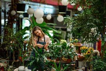 Florist taking care of a plant while using a smartphone