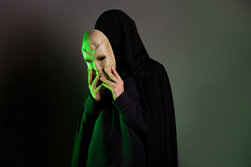 An anonymous villain, a hidden figure in a black cape with a hood. A mystical character with a...