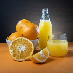 Closeup of moist oranges and glass bottle of orange juice on the table.