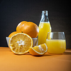 Closeup of moist oranges and glass bottle of orange juice on the table.