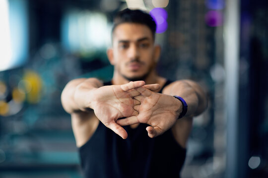Confident Young Arab Man Stretching Arms Before Training In Gym, Closeup Shot