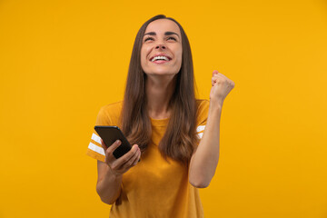 Euphoric footbal fan girl celebrating her favourite team victory and money win after betting at...