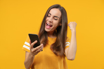 Portrait of euphoric soccer fan girl celebrating her favourite team victory and money win after betting at bookmaker's mobile application, making winner's gesture clenching her fist - 470961093