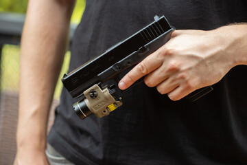 Male hand holding a black gun for playing airsoft