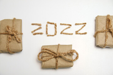 Brown eco gift boxes. Number 2022. Happy New year 2022. New Year Concept welcoming New Year 2022 written by craft rope or jute on white background. Two thousand twenty two. Isolated. Closeup