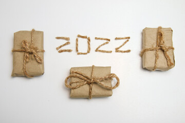 Brown eco gift boxes. Number 2022. Happy New year 2022. New Year Concept welcoming New Year 2022 written by craft rope or jute on white background. Two thousand twenty two. Frame. Isolated. Top view