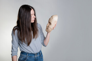 Complexes due to appearance or self-identification problems, concept. A young woman holds a mask in...