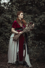 Fototapeta premium Witch with short hair in dress against the background of wild nature