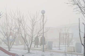 Silhouettes of people in thick fog on frosty cold morning