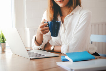 Beautiful woman using laptop at cafe while drinking coffee.