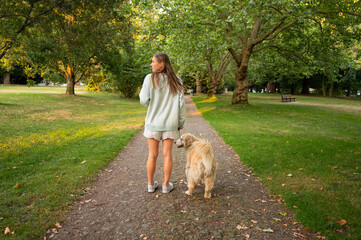 Girl walking her dog through a city park