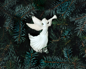 White angel with trumpet on evergreen tree branches creative layout. Christmas minimal background...