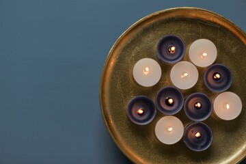Candle flame. Burning candles in a round gold tray on a blue background
