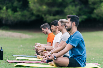 Group of four people doing lotus pose of yoga in a park