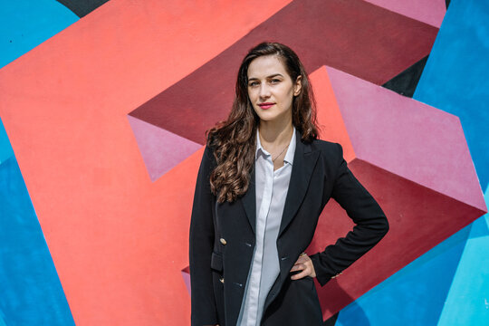 Confident young female manager standing near graffiti wall